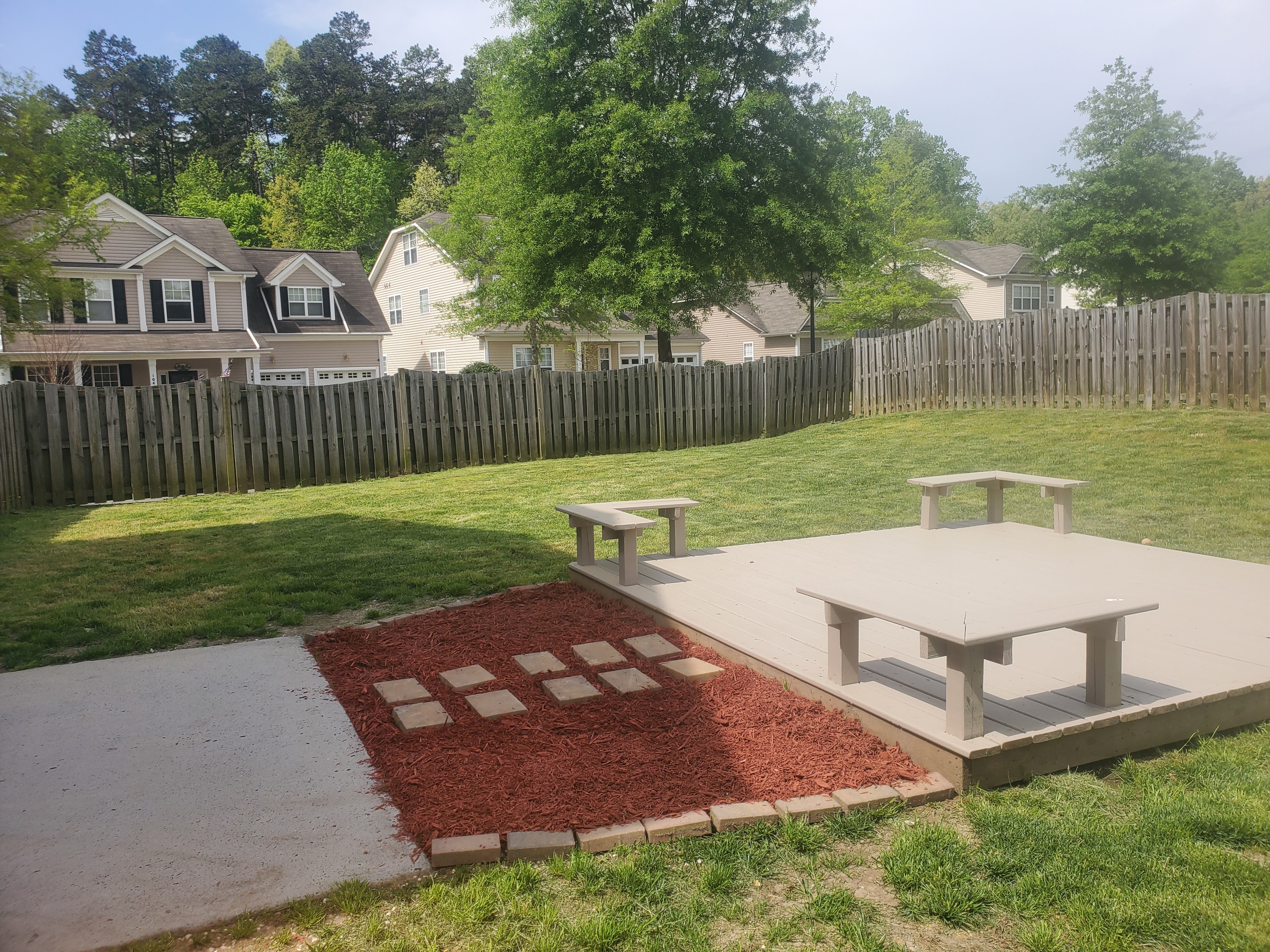 Backyard with deck, red mulch beds, and stepping stones