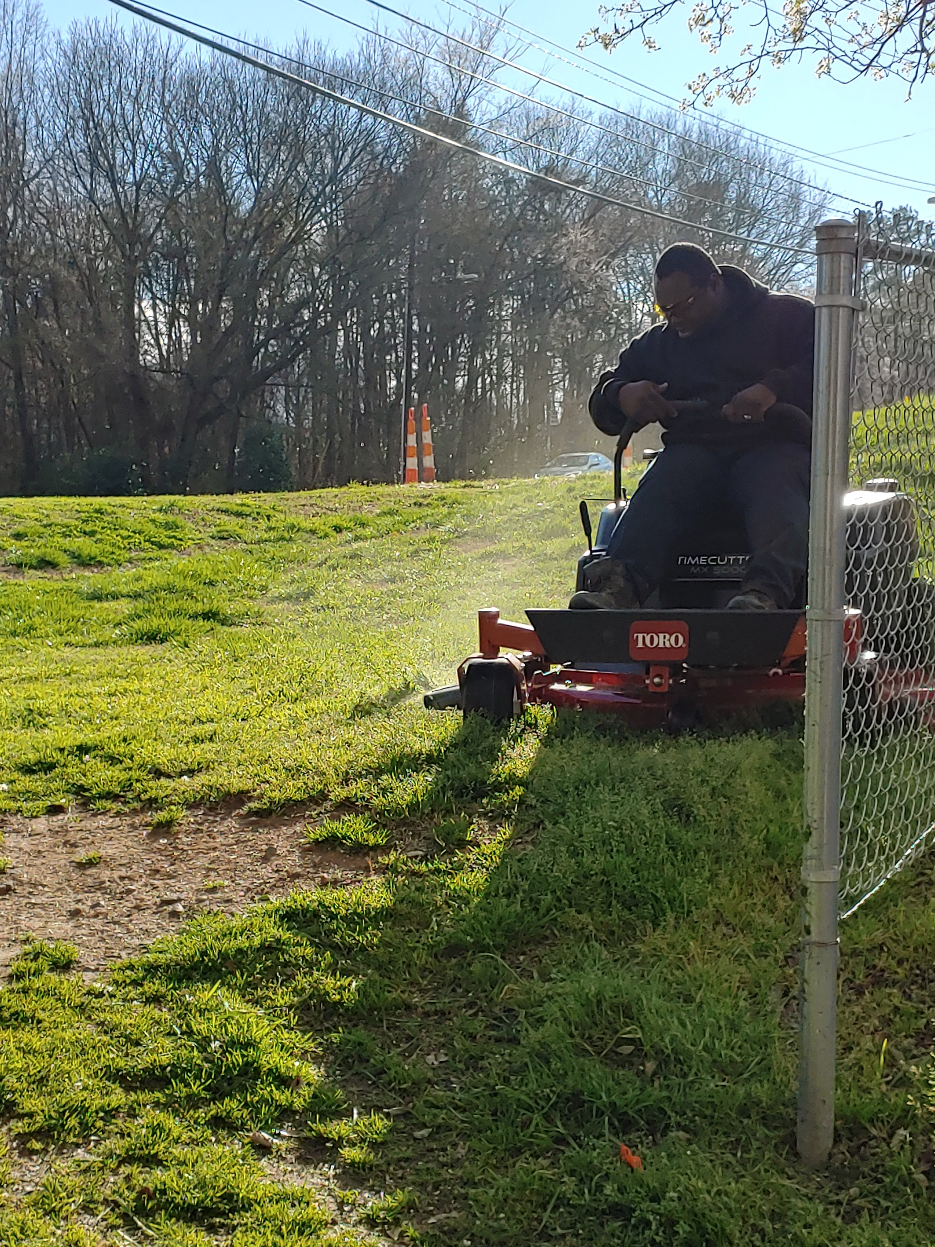 Tito Grant operating a TORO riding mower along a fence line